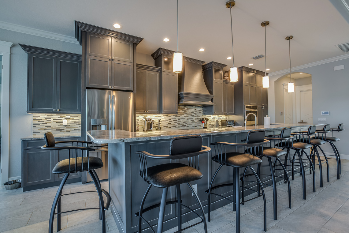 Dark gray cabinets and pendant lights adorn this classy kitchen